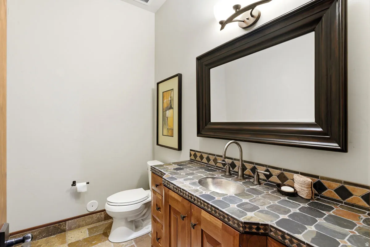 Vanity featuring a mosaic tile countertop, undermount sink, and wood cabinetry
