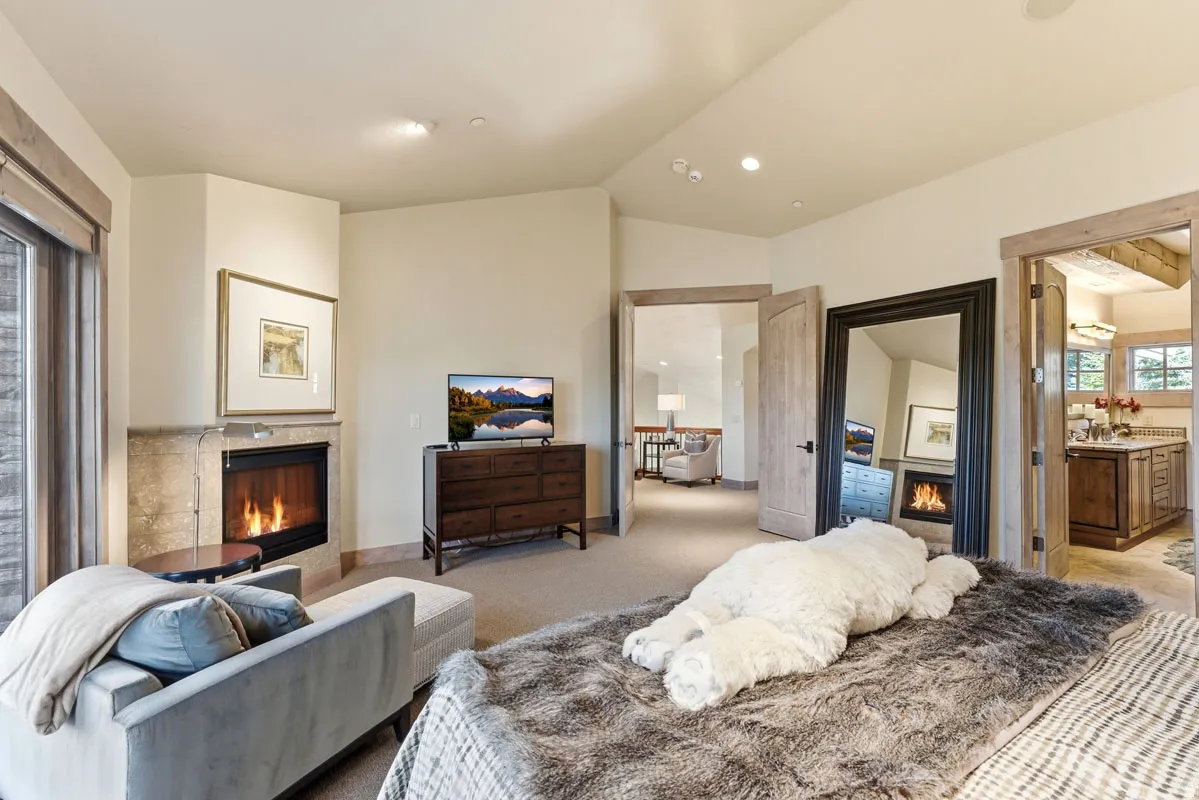 Corner fireplace with stone surround, wood-trim window, and wood-finish door frames