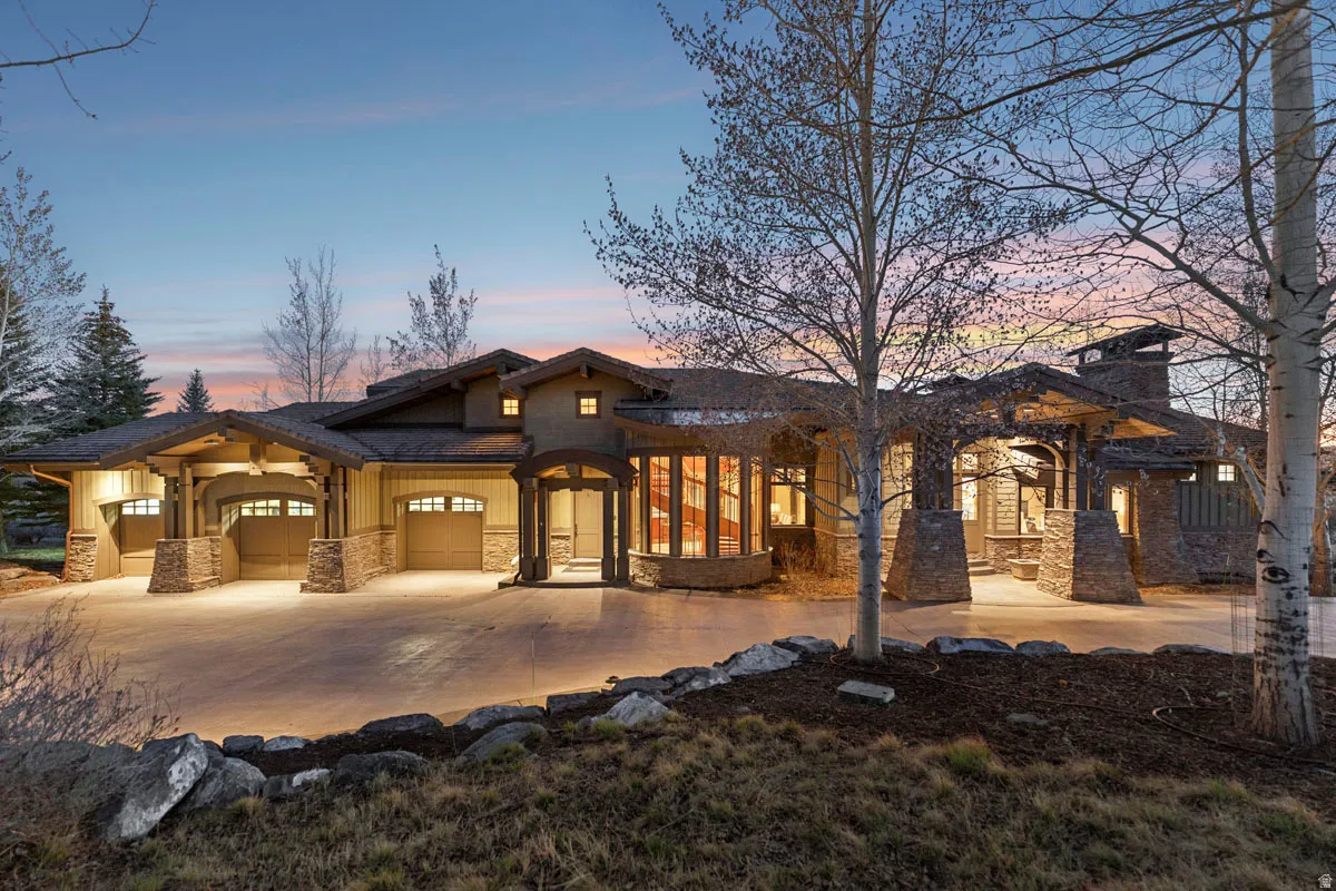 Expansive Craftsman-style residence featuring a stone and stucco exterior, multiple attached garages, a porte-cochère, and a stone chimney