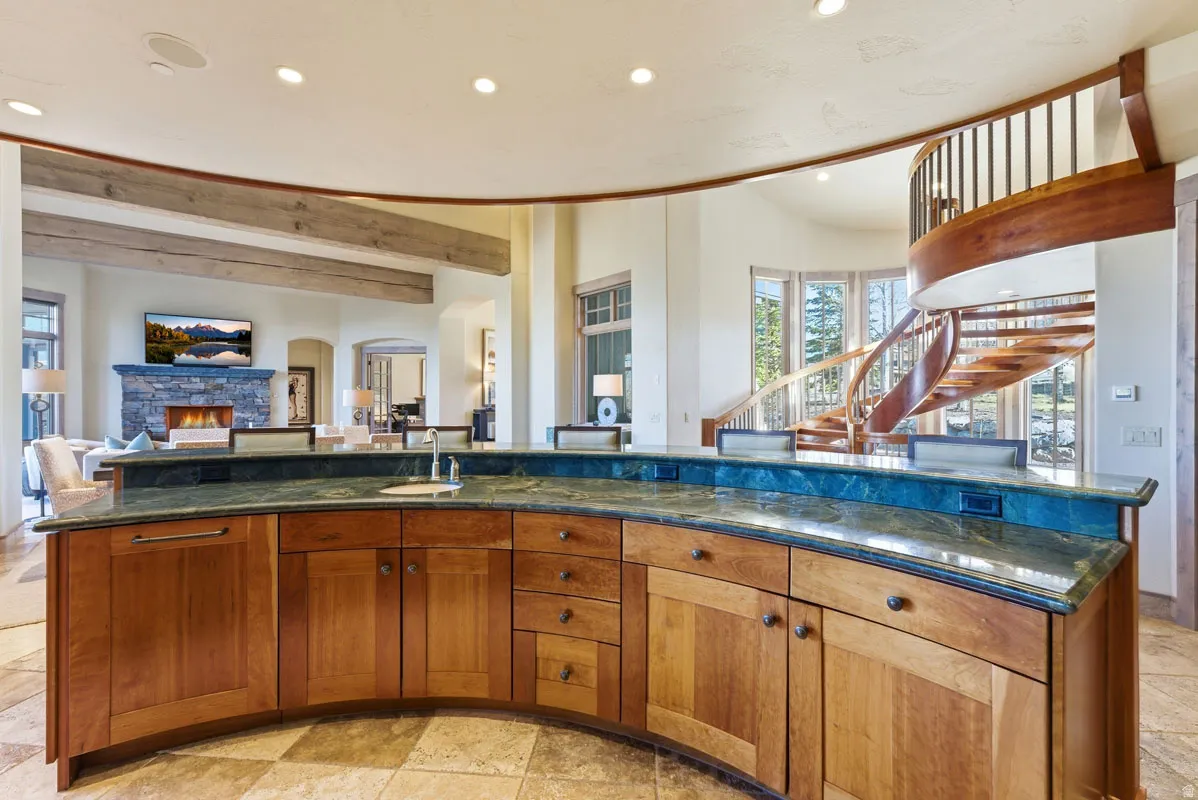 Curved wood cabinetry with a countertop sink and green stone surfaces