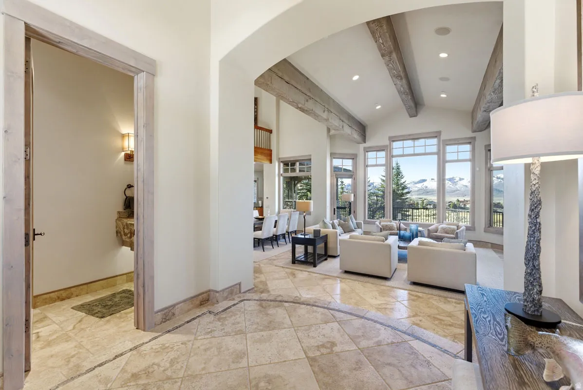 Vaulted ceiling living room featuring exposed wood beams, extensive window array, recessed lighting, and tiled flooring
