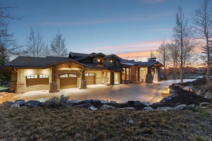 Sprawling Craftsman-style exterior featuring a multi-car garage, stone accents, horizontal siding, and a concrete driveway