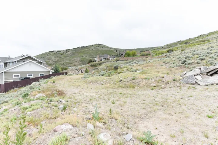 Sloping terrain featuring natural vegetation and distant hillside residences