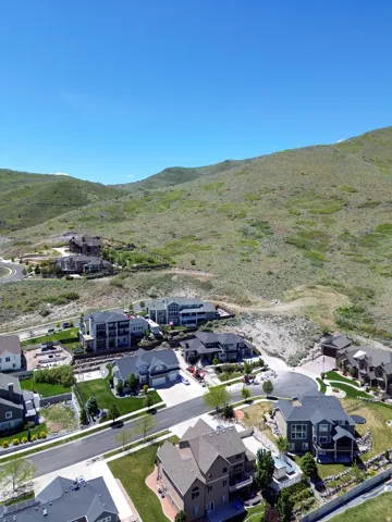Residential neighborhood featuring properties with varied architectural styles, mature landscaping, and an expansive natural hillside backdrop