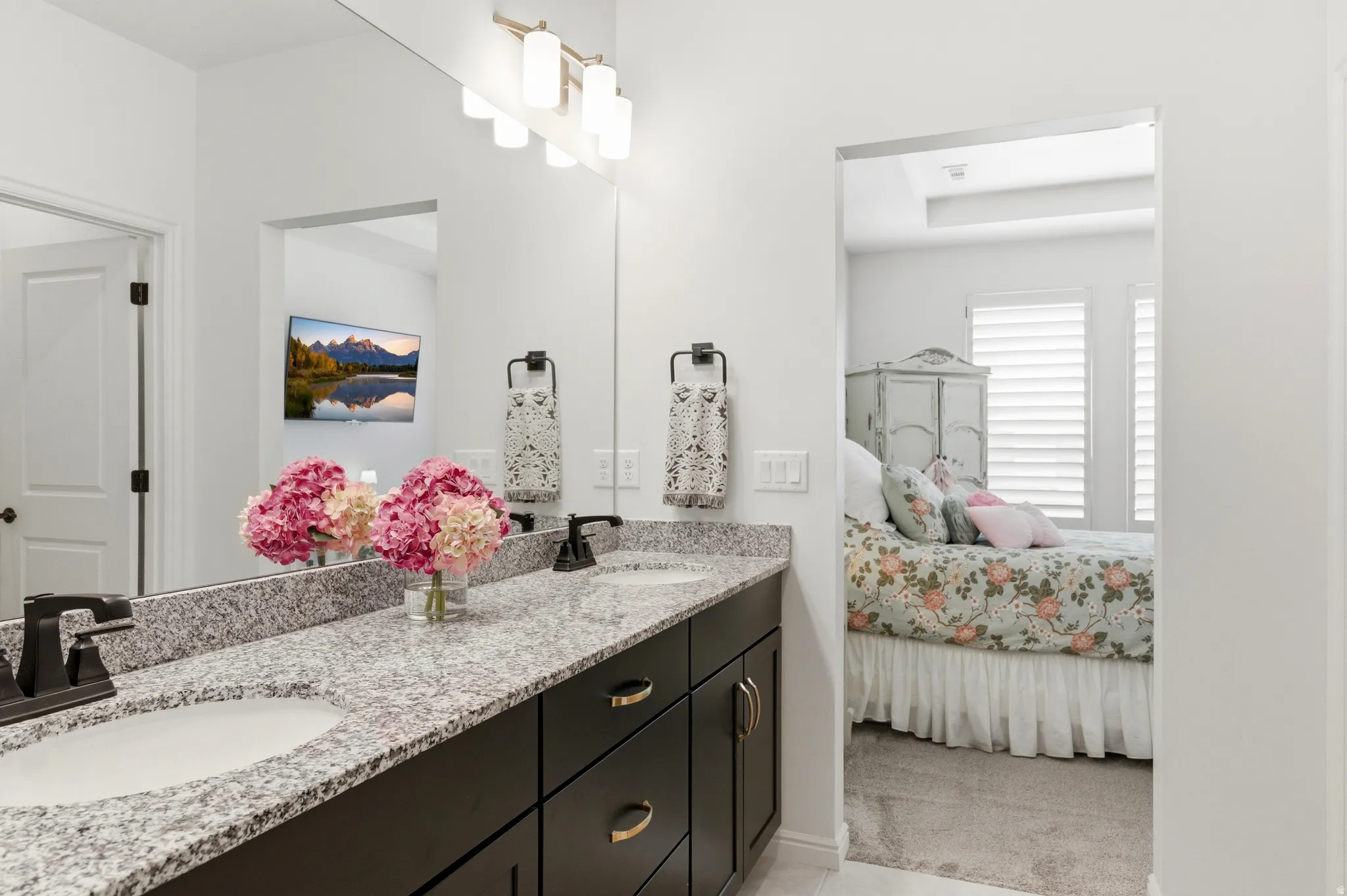 Double vanity with granite countertop, integrated sinks, dark wood-finish cabinetry, and matte black fixtures