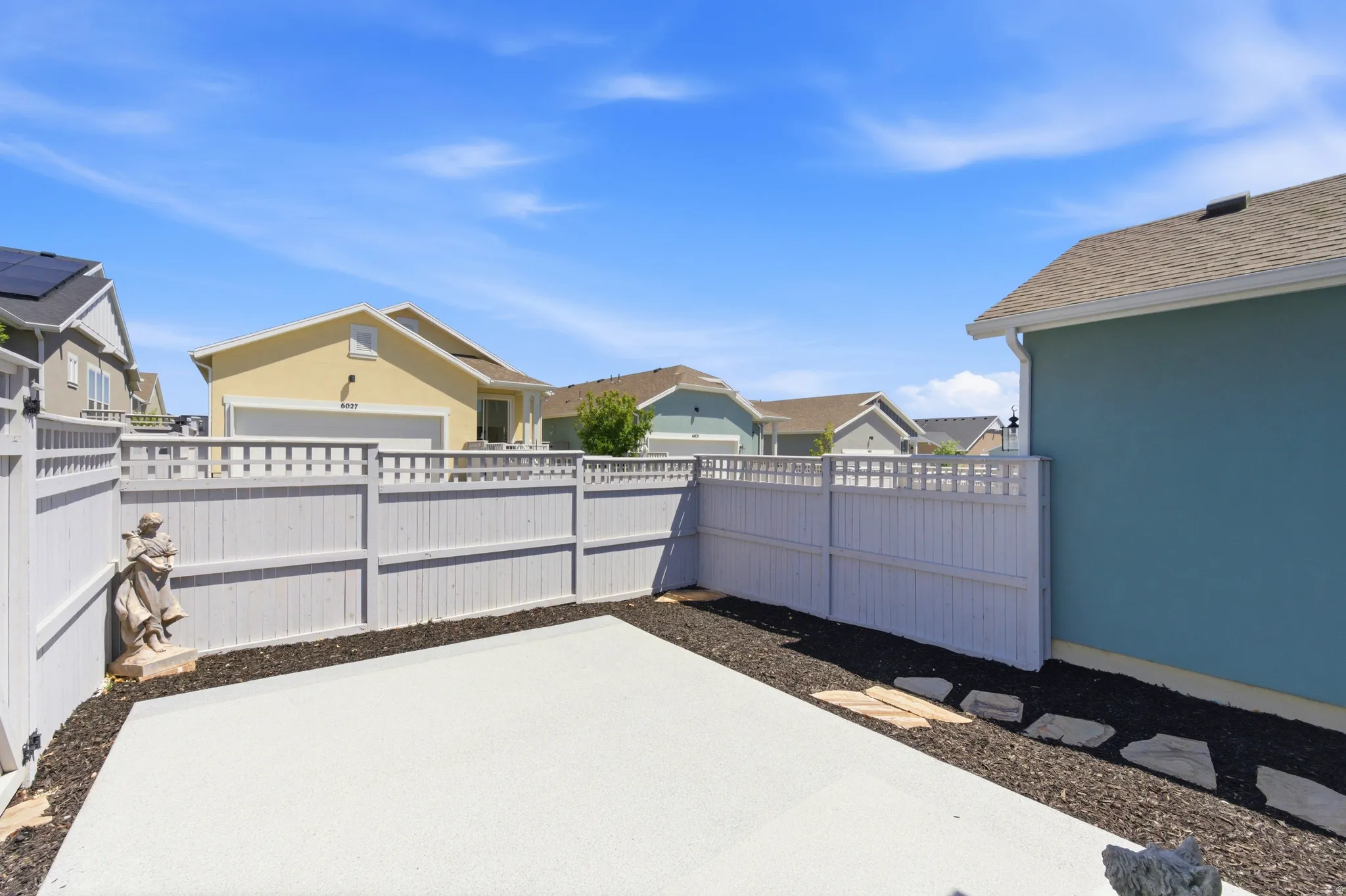 Backyard featuring a concrete patio, perimeter fencing, and dark ground cover
