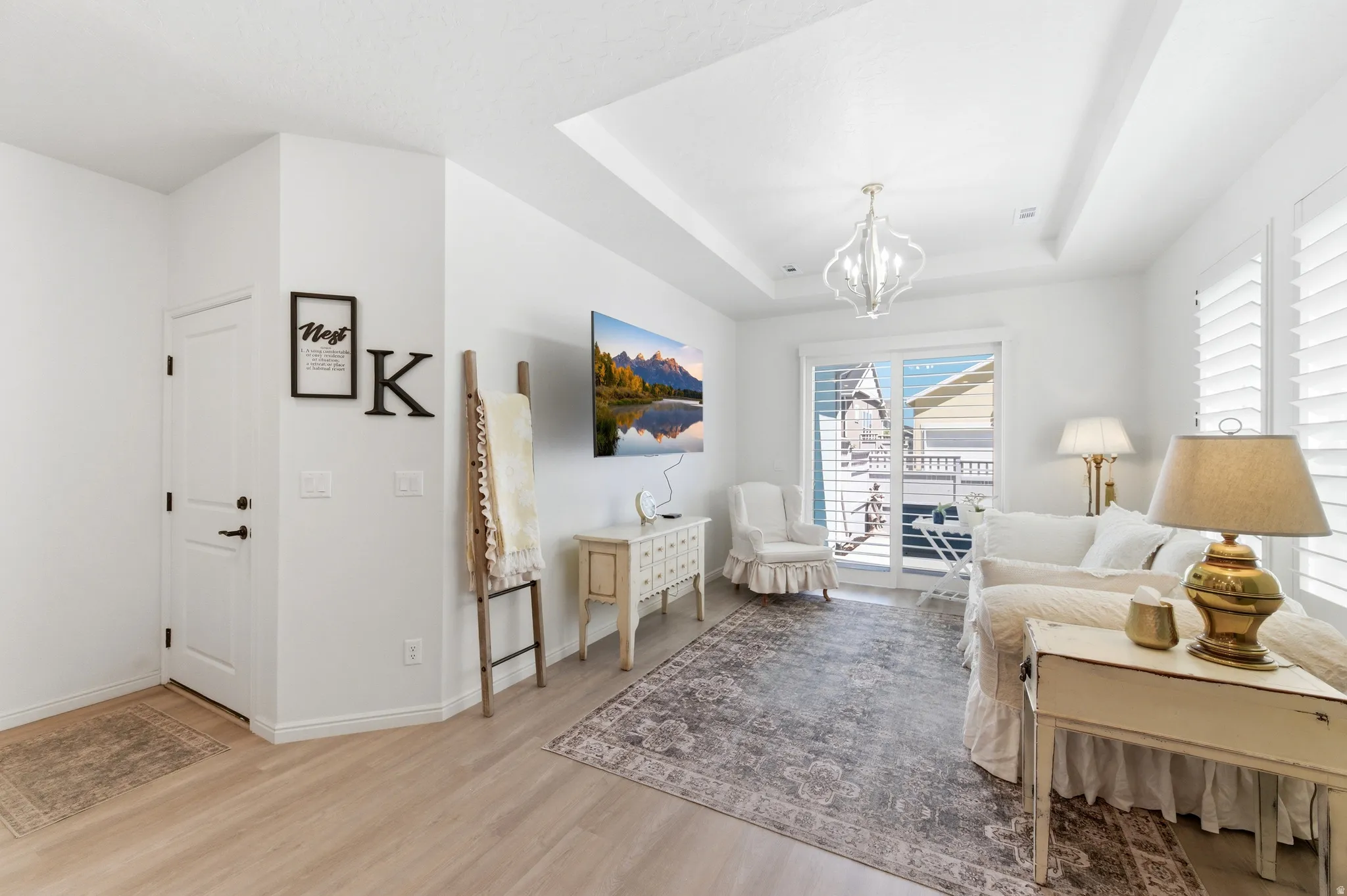 Open concept living space featuring a tray ceiling, wood-finish flooring, and white plantation shutters