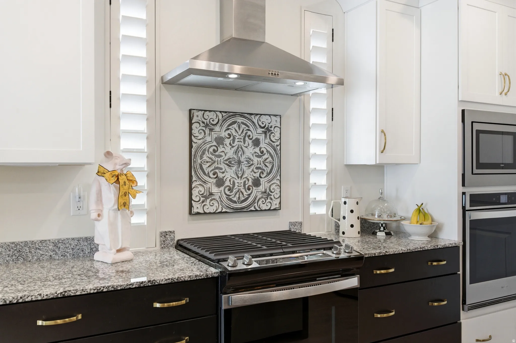 Stainless steel range hood over a black gas range with granite countertops