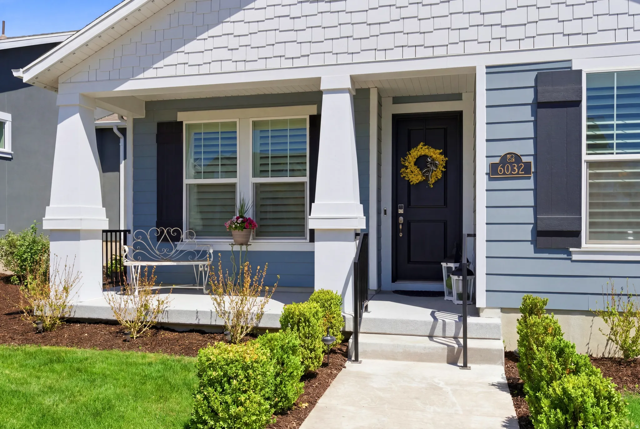 Front exterior featuring light blue siding, white trim, and a covered porch