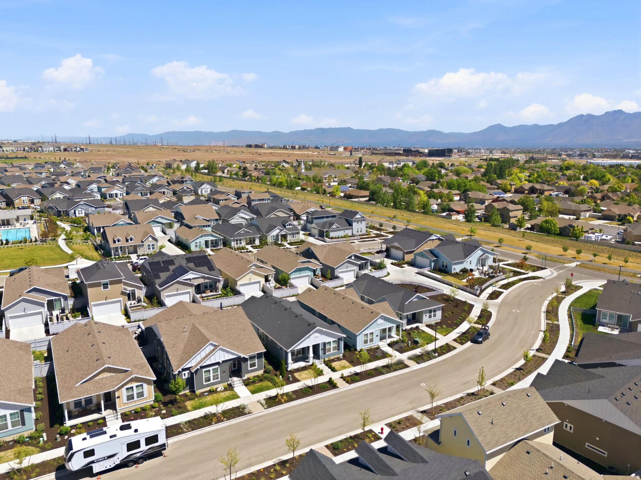Expansive aerial showcasing a modern residential development featuring numerous single-family homes with varied architectural styles and rooflines