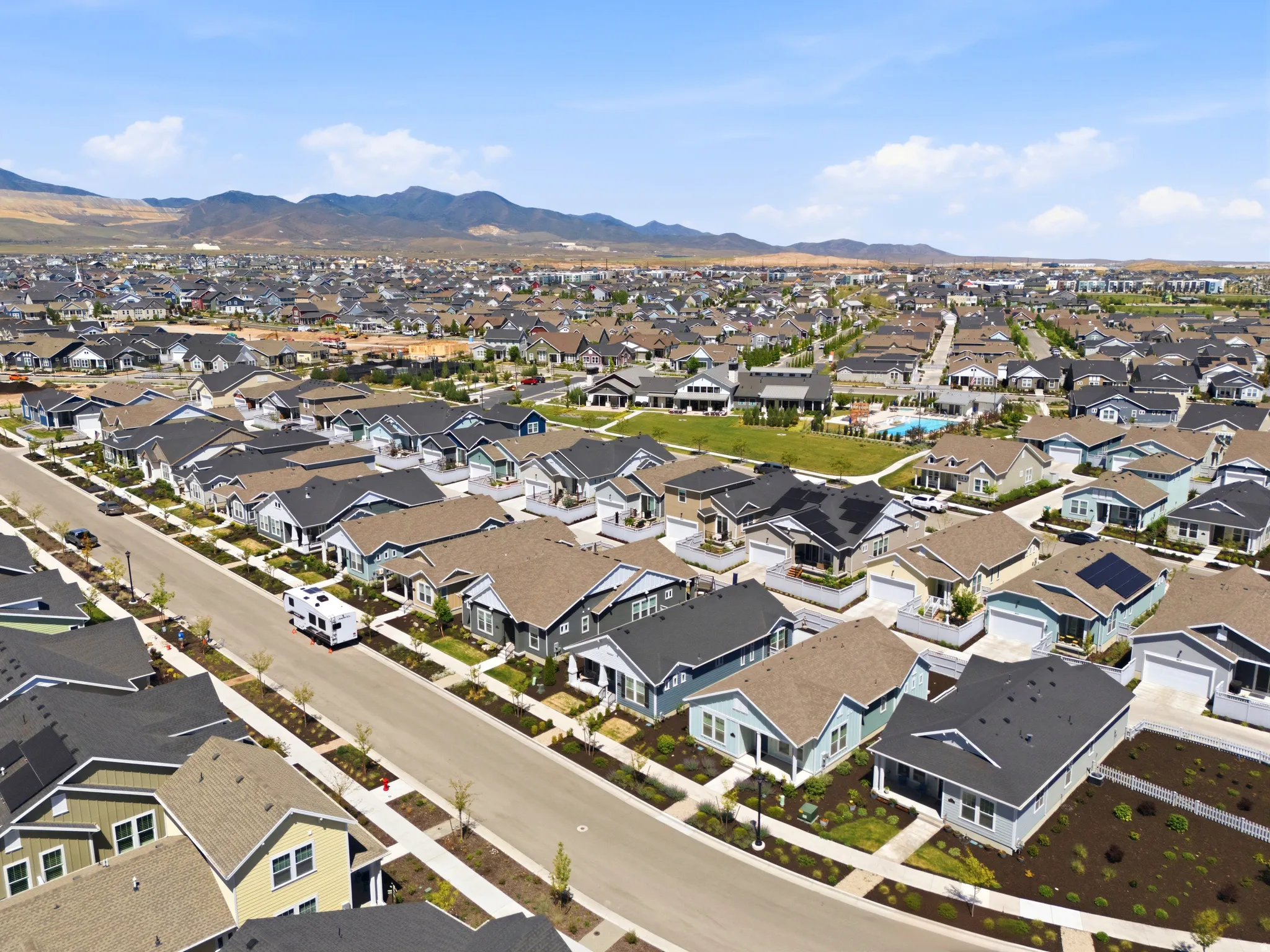 Expansive community featuring numerous single-family homes with varied architectural styles, a paved street, and mature landscaping
