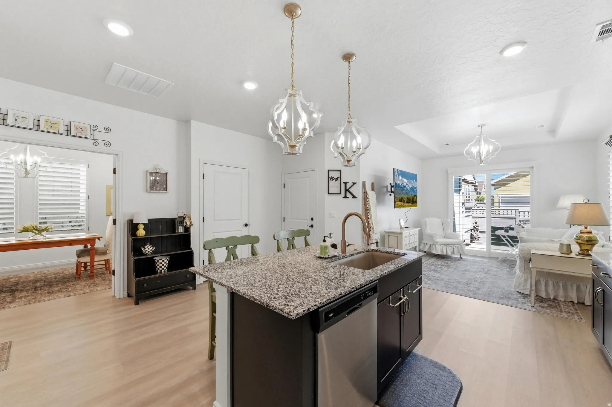 Open-concept kitchen featuring an island with granite countertops, an undermount sink, and stainless steel dishwasher