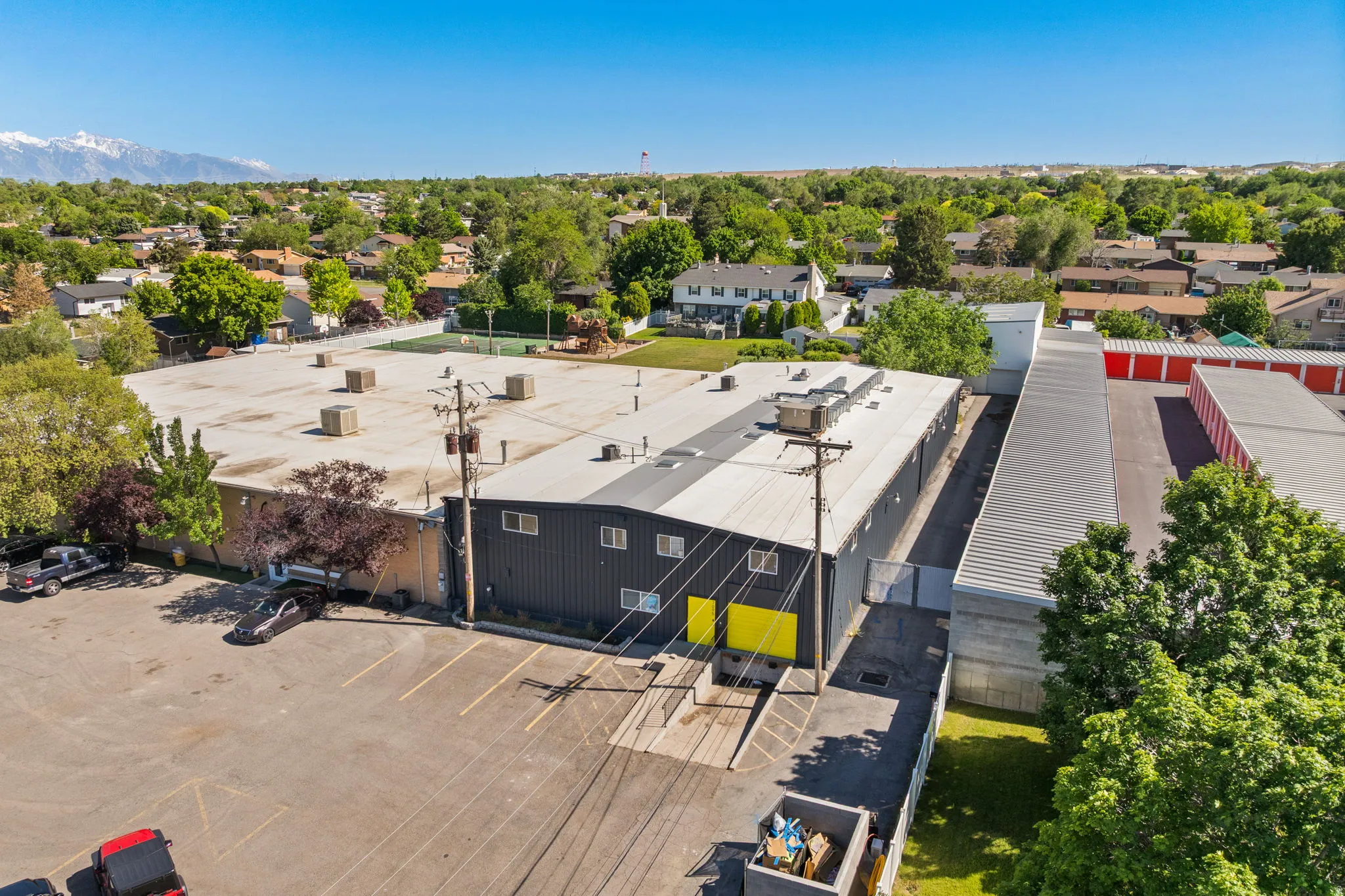 Commercial building featuring a dark grey facade with bright yellow accents, multiple windows, and a flat roof