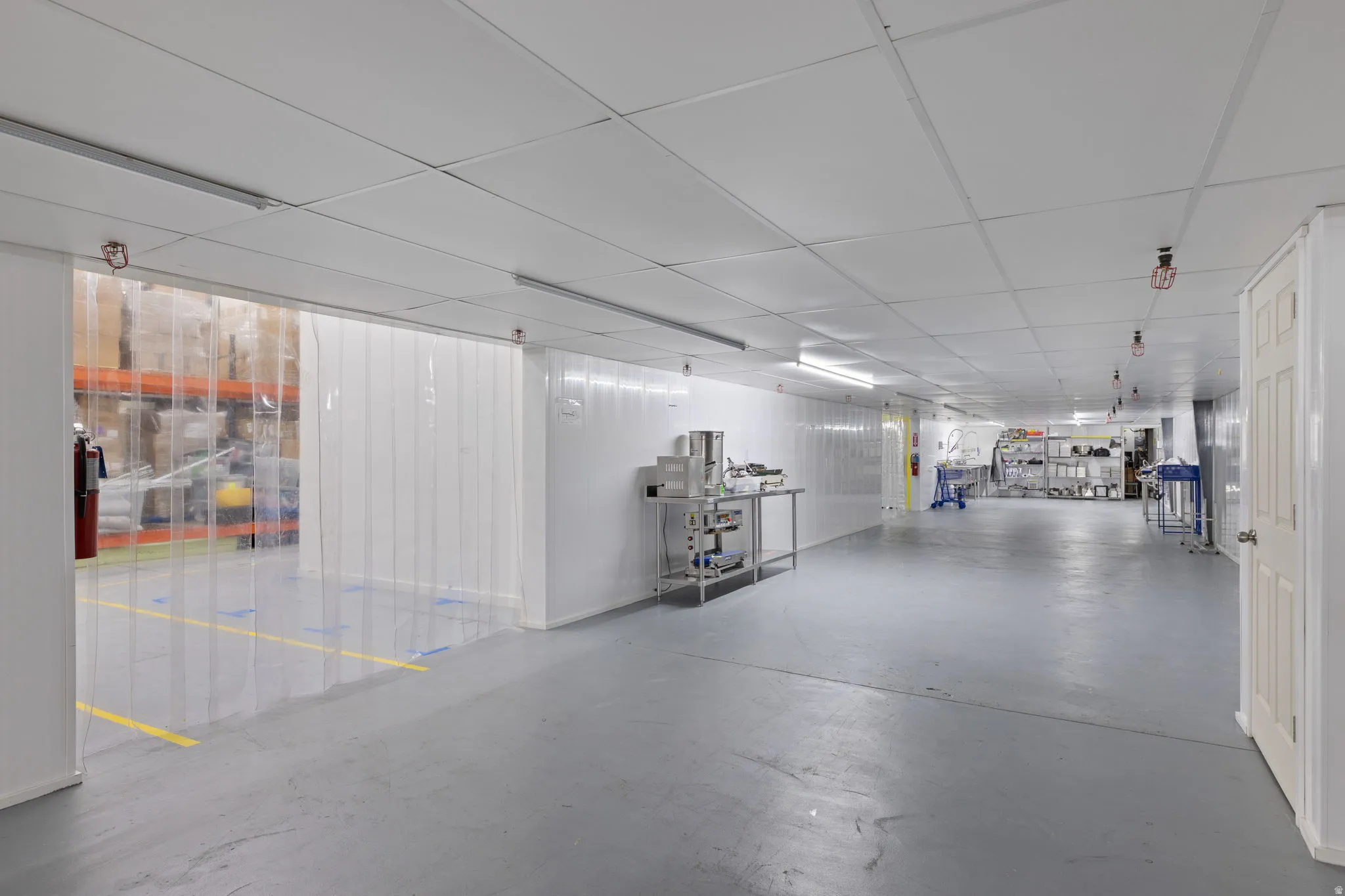 Spacious commercial interior featuring resilient flooring, drop ceiling with integrated lighting, and multiple access points