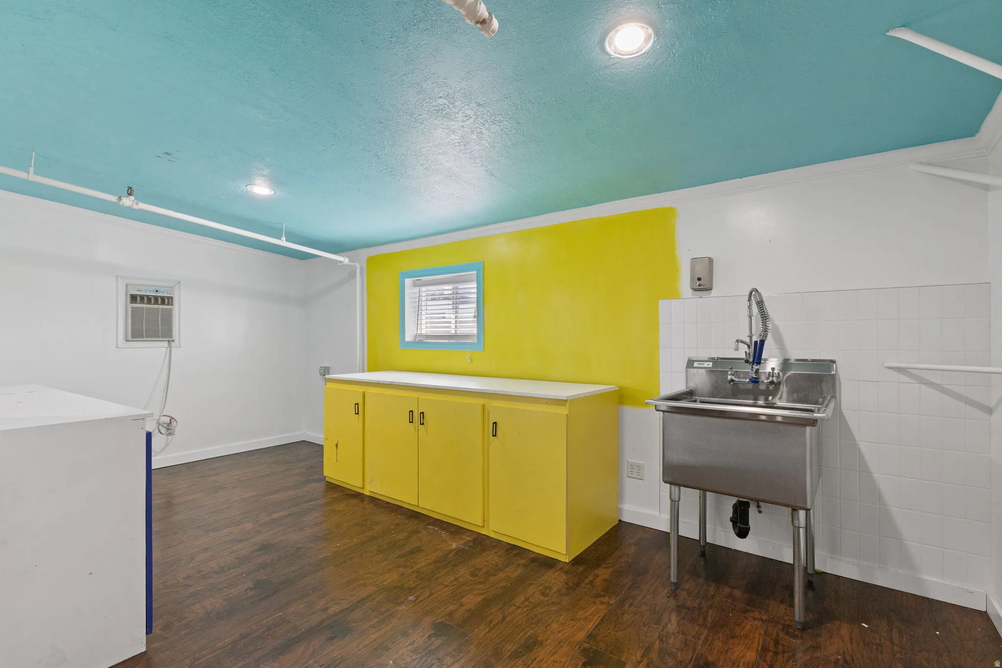 Room featuring wood-finish flooring, a bright blue ceiling with recessed lighting, and white walls