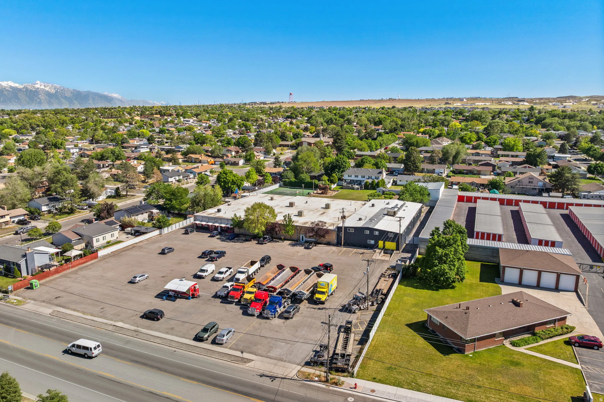 Large commercial property featuring extensive paved parking, multiple building structures, and an adjacent self-storage facility