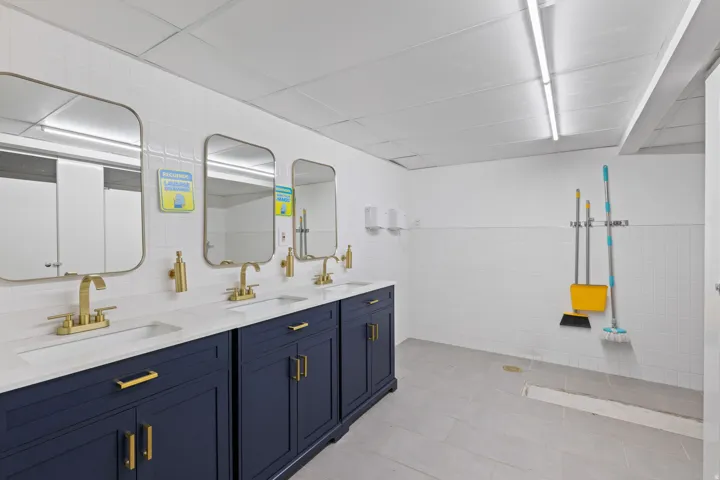 Multiple vanity stations featuring white countertops, undermount sinks, and gold-finish faucets