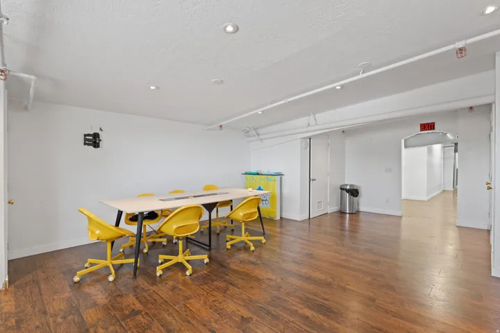 Spacious room featuring wood-finish flooring, white walls, and recessed lighting