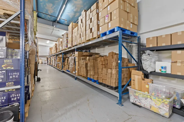 Industrial warehouse space featuring concrete flooring and high ceilings with fluorescent lighting
