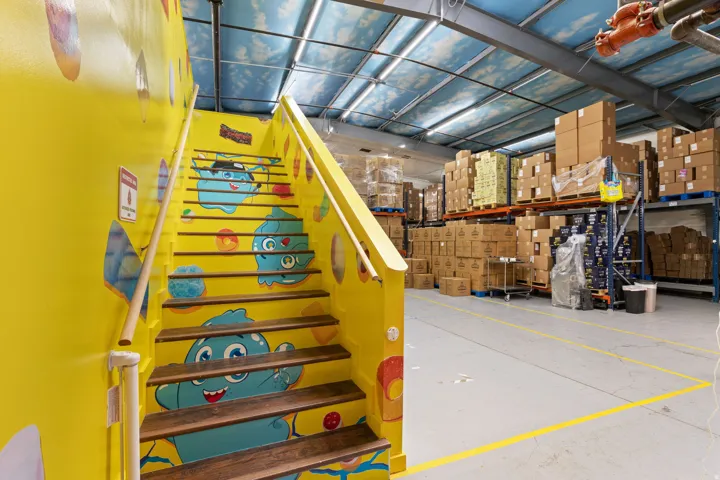 Yellow-painted staircase with wood-finish treads and a light wood-finish handrail, featuring colorful character decals