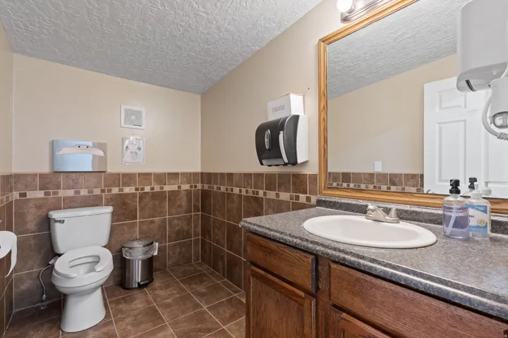 Bathroom featuring a wood-finish vanity with an integrated sink, a large framed mirror, and a toilet