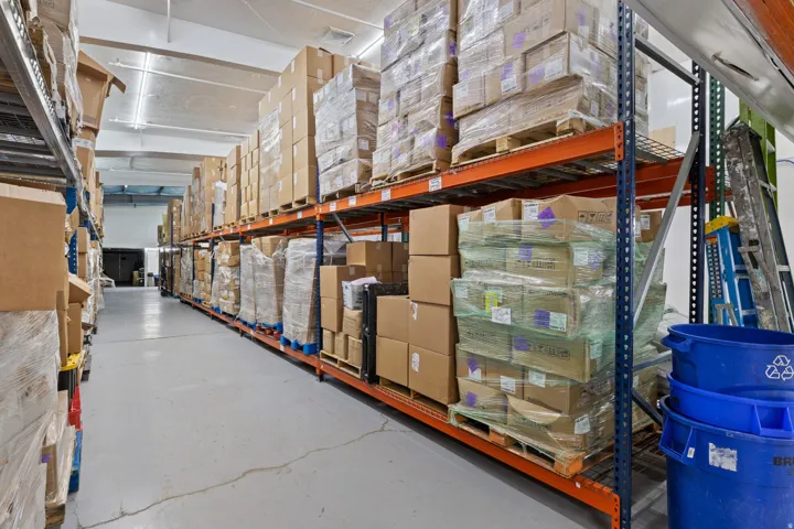 Warehouse interior featuring high-bay shelving systems, polished concrete flooring, and fluorescent lighting fixtures