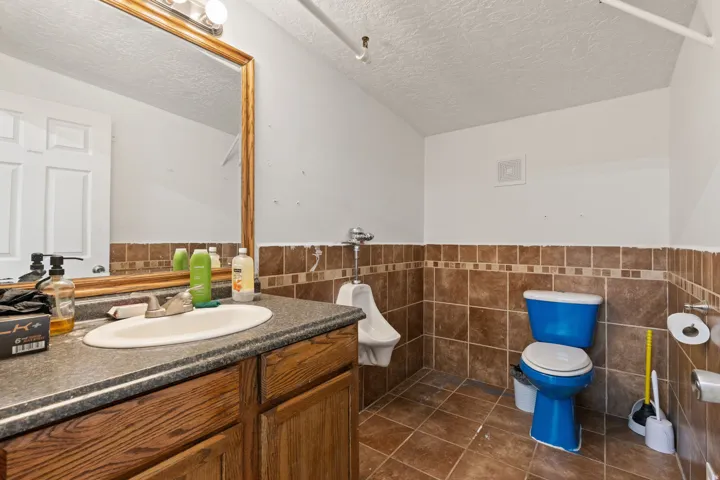 Bathroom featuring a vanity with a rectangular sink, a large wall-mounted mirror, and tile flooring