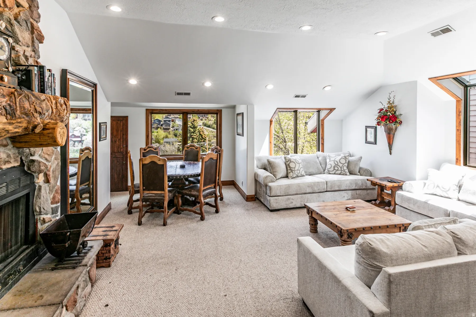 Expansive living area with recessed lighting, a stone fireplace, and a natural wood mantel