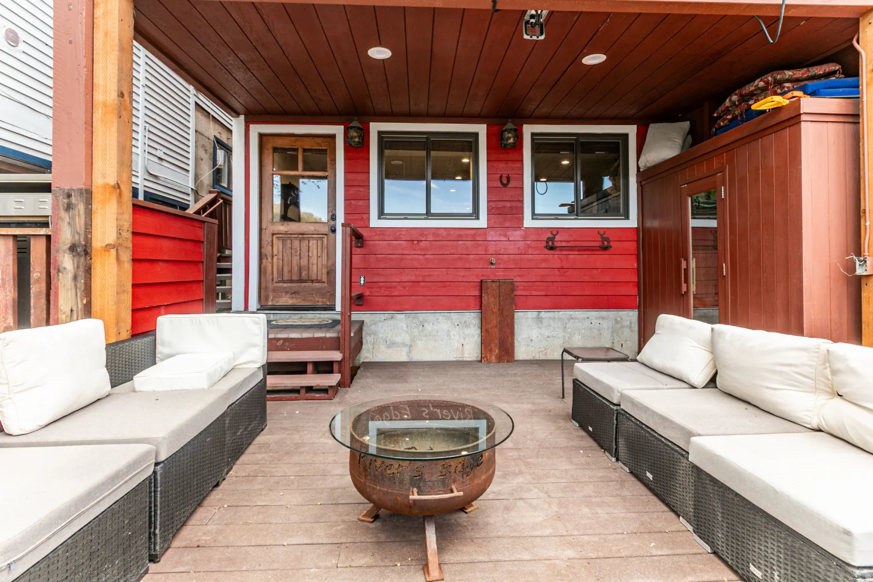 Covered patio with wood-finish flooring and a rich red siding backdrop