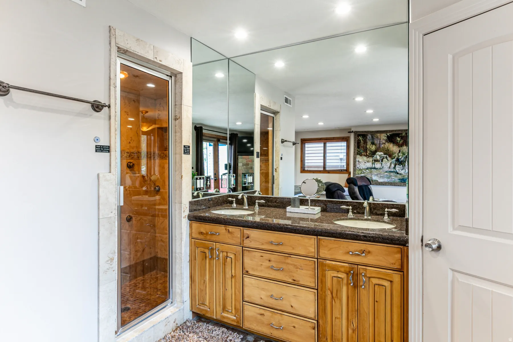Bathroom featuring a double vanity with wood cabinetry and a dark stone countertop