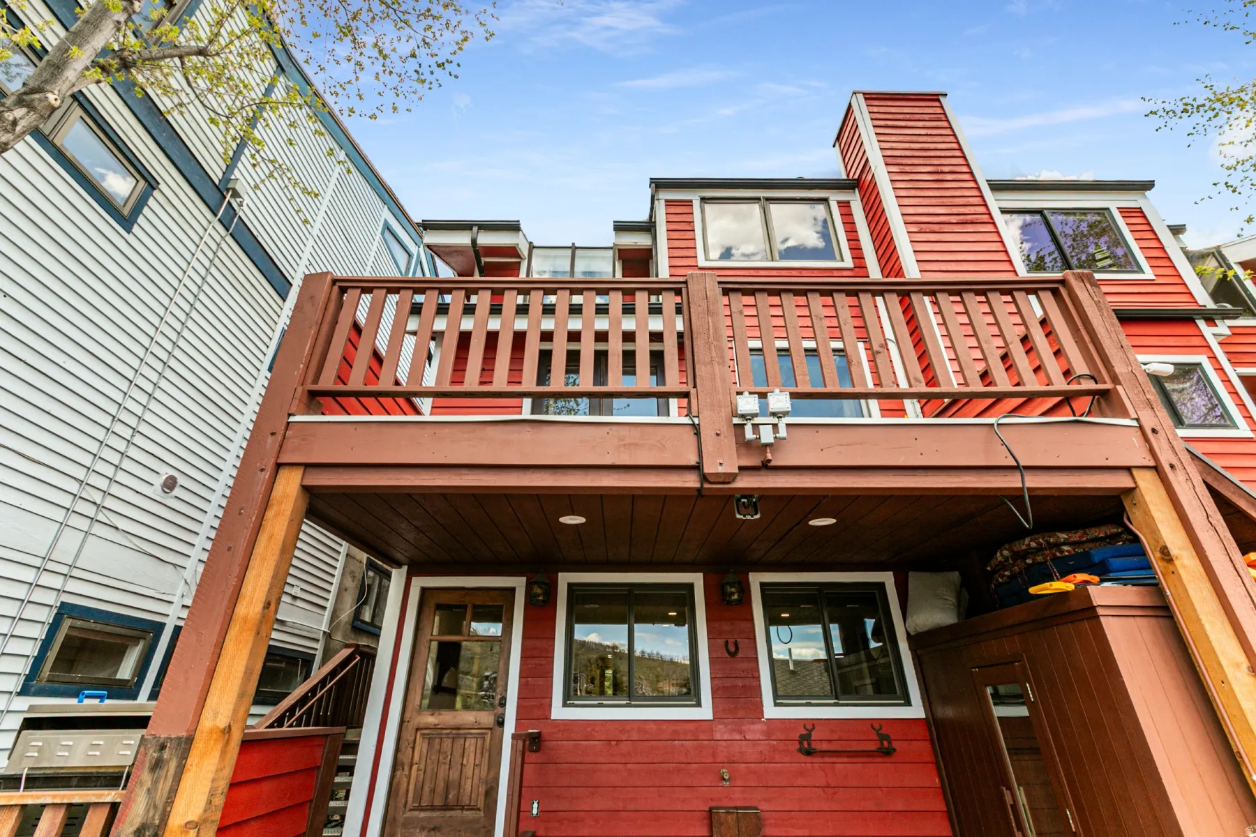 Multi-level exterior featuring red siding and a prominent wood deck