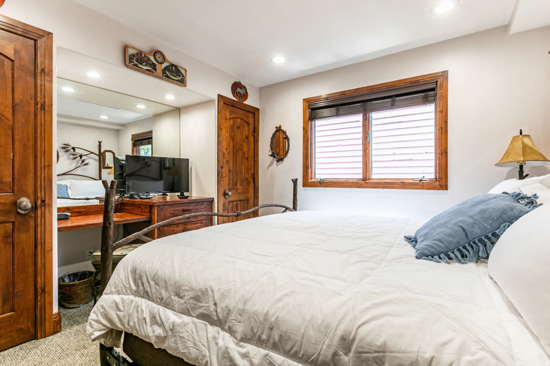 Bedroom featuring natural wood doors and window trim, recessed lighting, a built-in desk area with mirrored wall, and textured carpeting