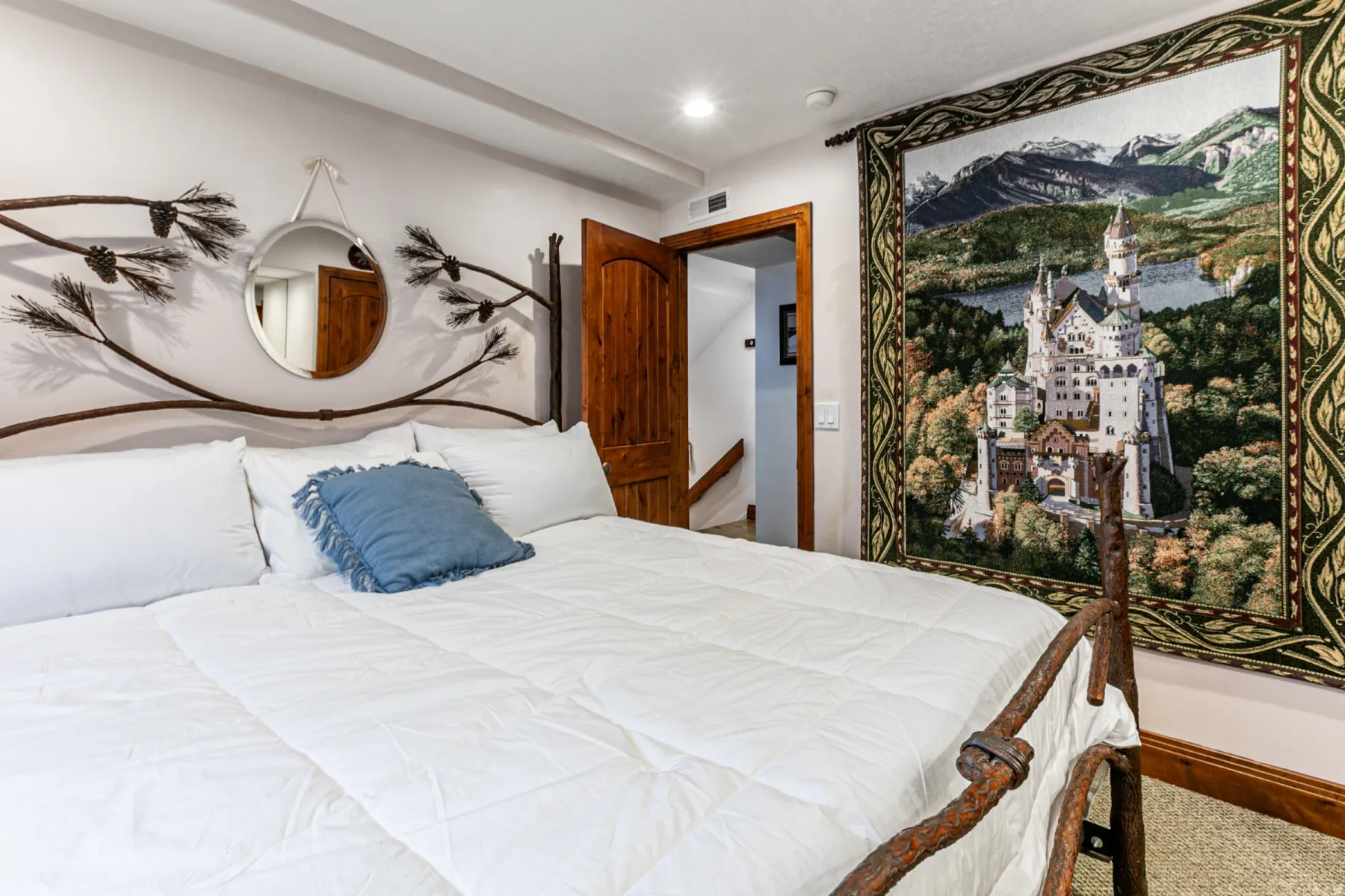 Recessed ceiling lighting illuminates a bedroom with a natural wood paneled door and trim