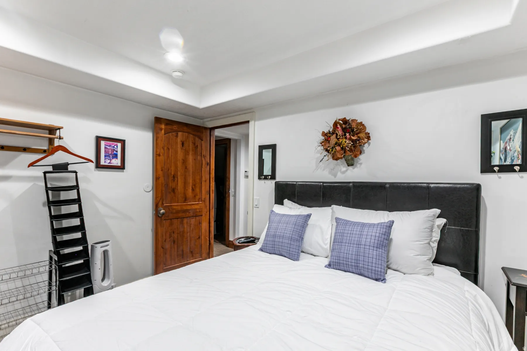 Bedroom featuring a tray ceiling with recessed lighting, wood door, and a built-in wall shelf