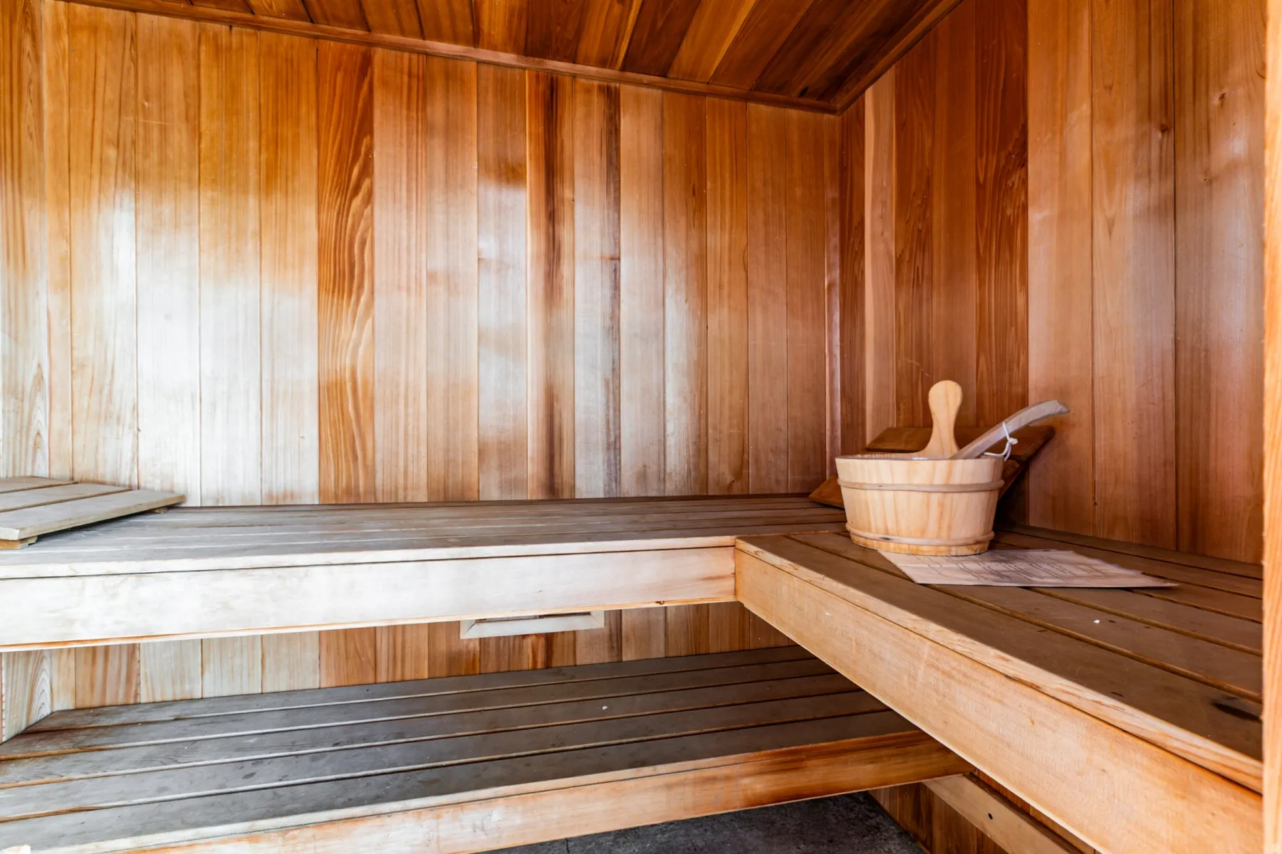 Interior wood-paneled sauna featuring multi-level wooden benches and slatted flooring
