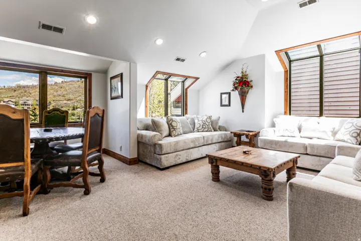 Expansive carpeted living area featuring recessed lighting, multiple windows with wooded frames, and a distinctive angled ceiling