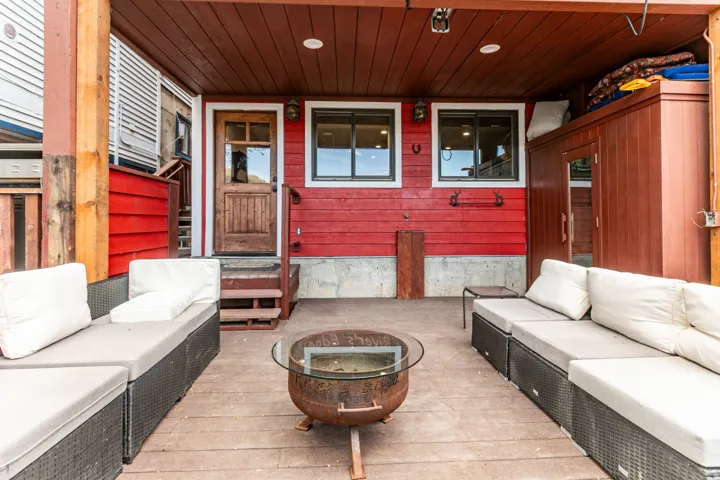 Covered patio with wood-finish flooring and a rich red siding backdrop