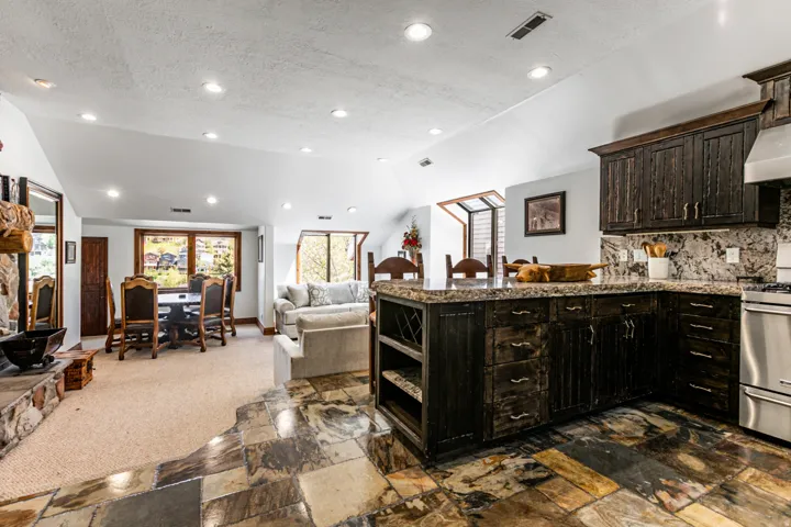 Kitchen featuring dark-stained wood cabinetry, stone countertops, and a full-height tile backsplash