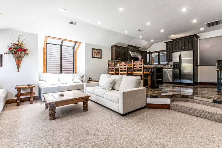Open-concept living space featuring vaulted ceilings, recessed lighting, and light-toned carpeting