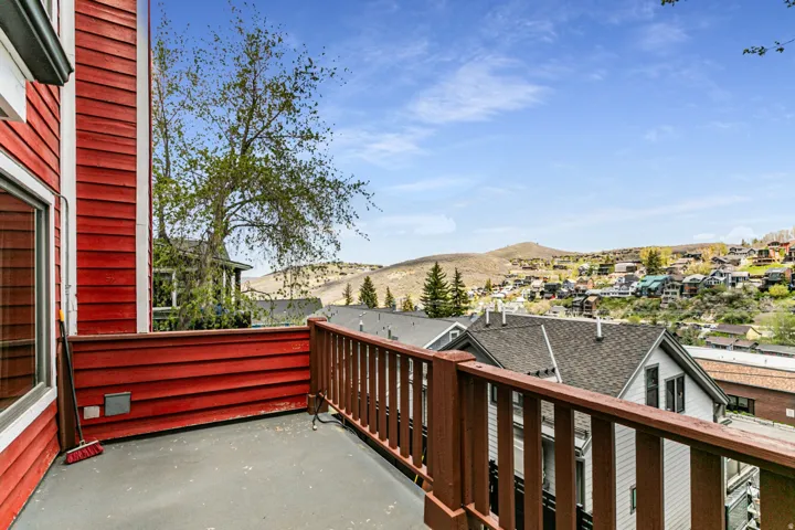 Exterior deck with a brown wood railing, red horizontal siding, and a gray floor