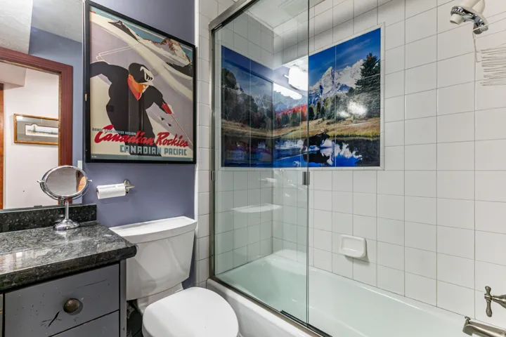 Bathroom featuring a shower-tub combination with clear glass enclosure and white tile surround