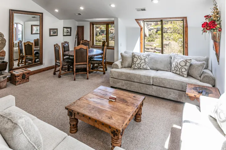 Carpeted living space featuring a window with a wooded backdrop, recessed lighting, and a prominent full-length mirror