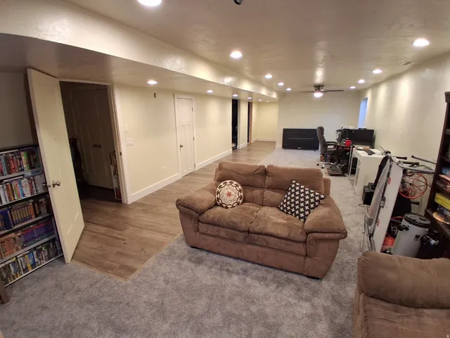 Spacious lower level featuring plush gray carpeting, wood-finish flooring, recessed lighting, a ceiling fan, and multiple interior doors
