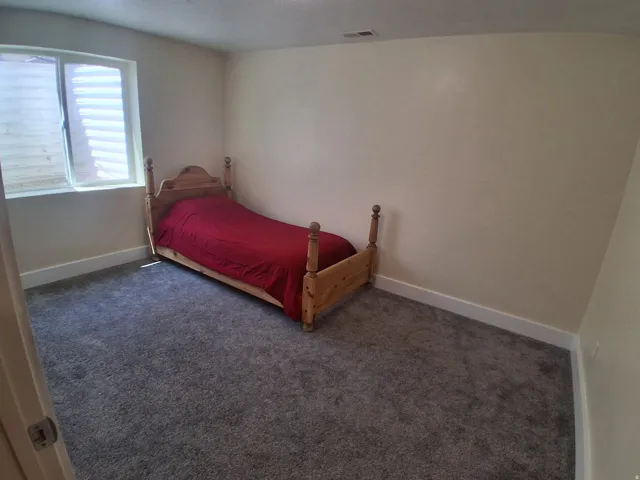 Carpeted room with a single window, light-colored walls, and white baseboards