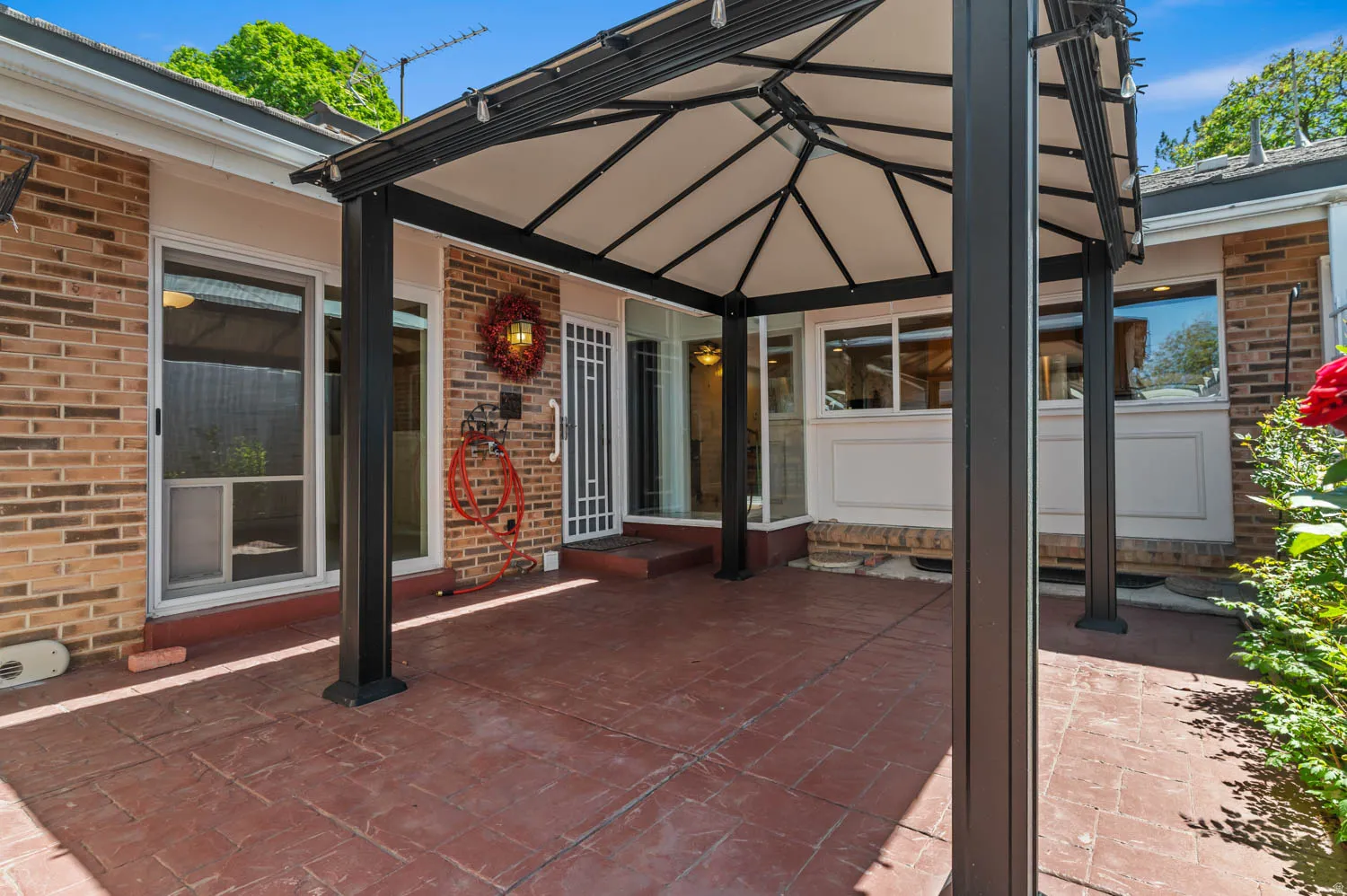 Expansive stamped concrete patio featuring a permanent gazebo structure with a white canopy