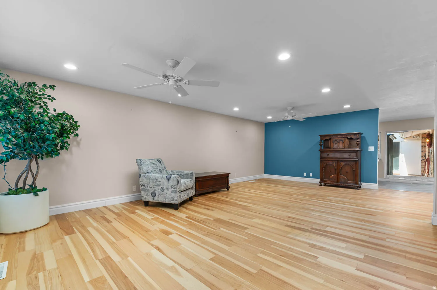 Spacious room featuring natural wood-finish flooring, recessed lighting, and a ceiling fan