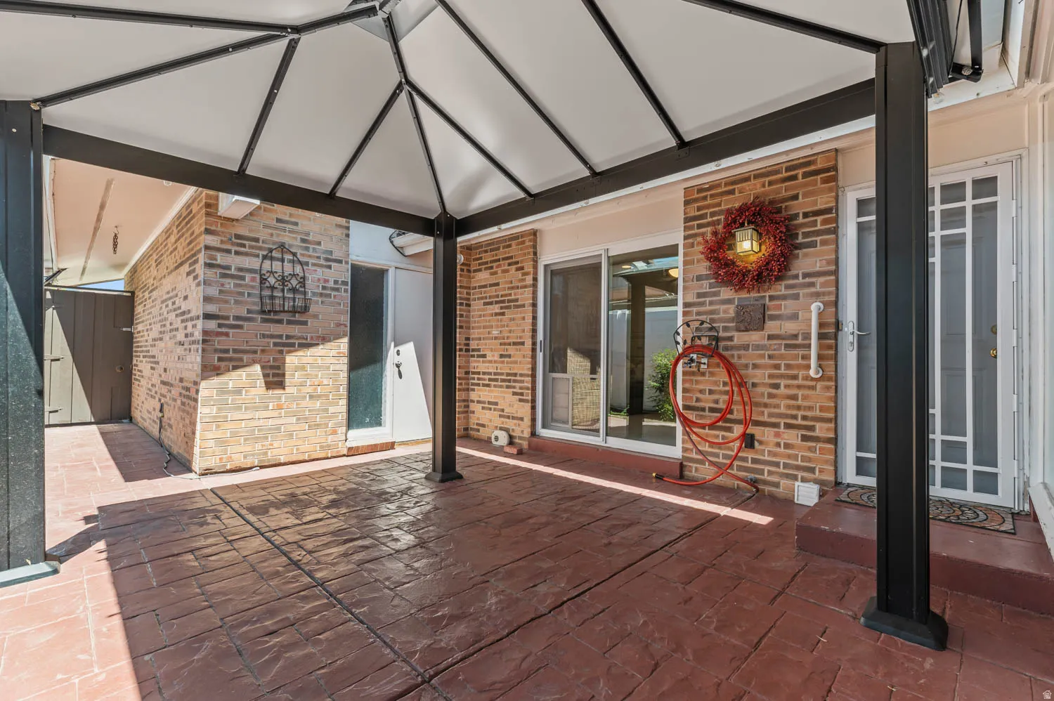 Covered patio featuring a stamped concrete surface and an exposed brick exterior