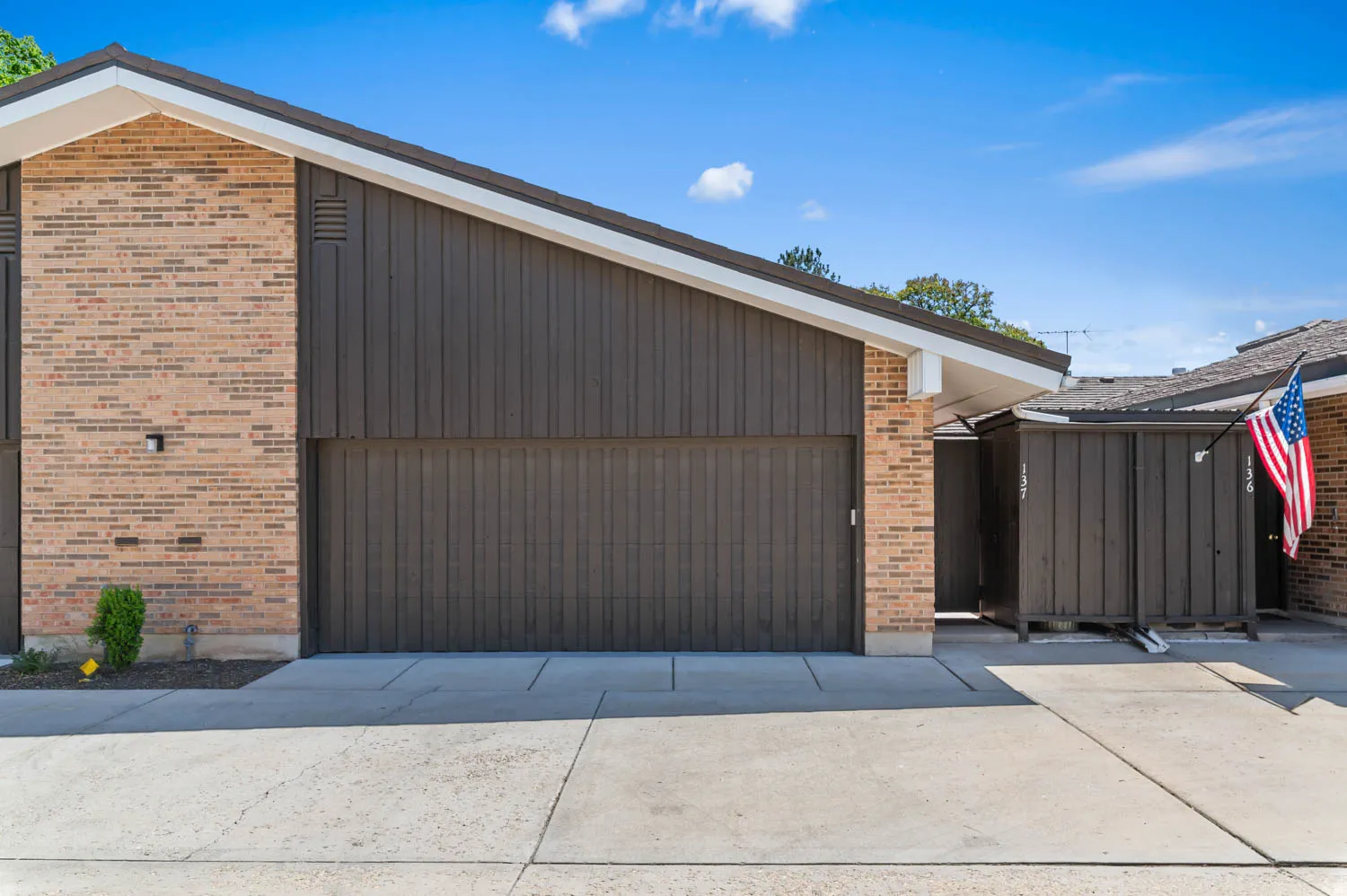 Exterior featuring a brown vertical siding garage door and brick facade