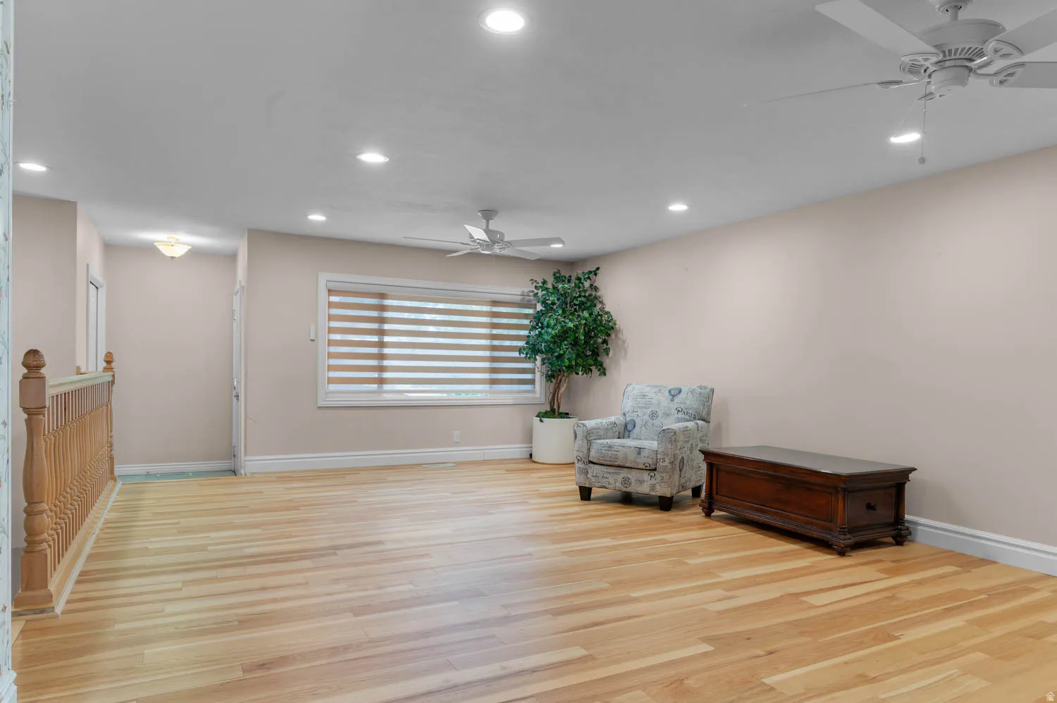 Spacious room featuring wood-finish flooring, recessed lighting, and two ceiling fans