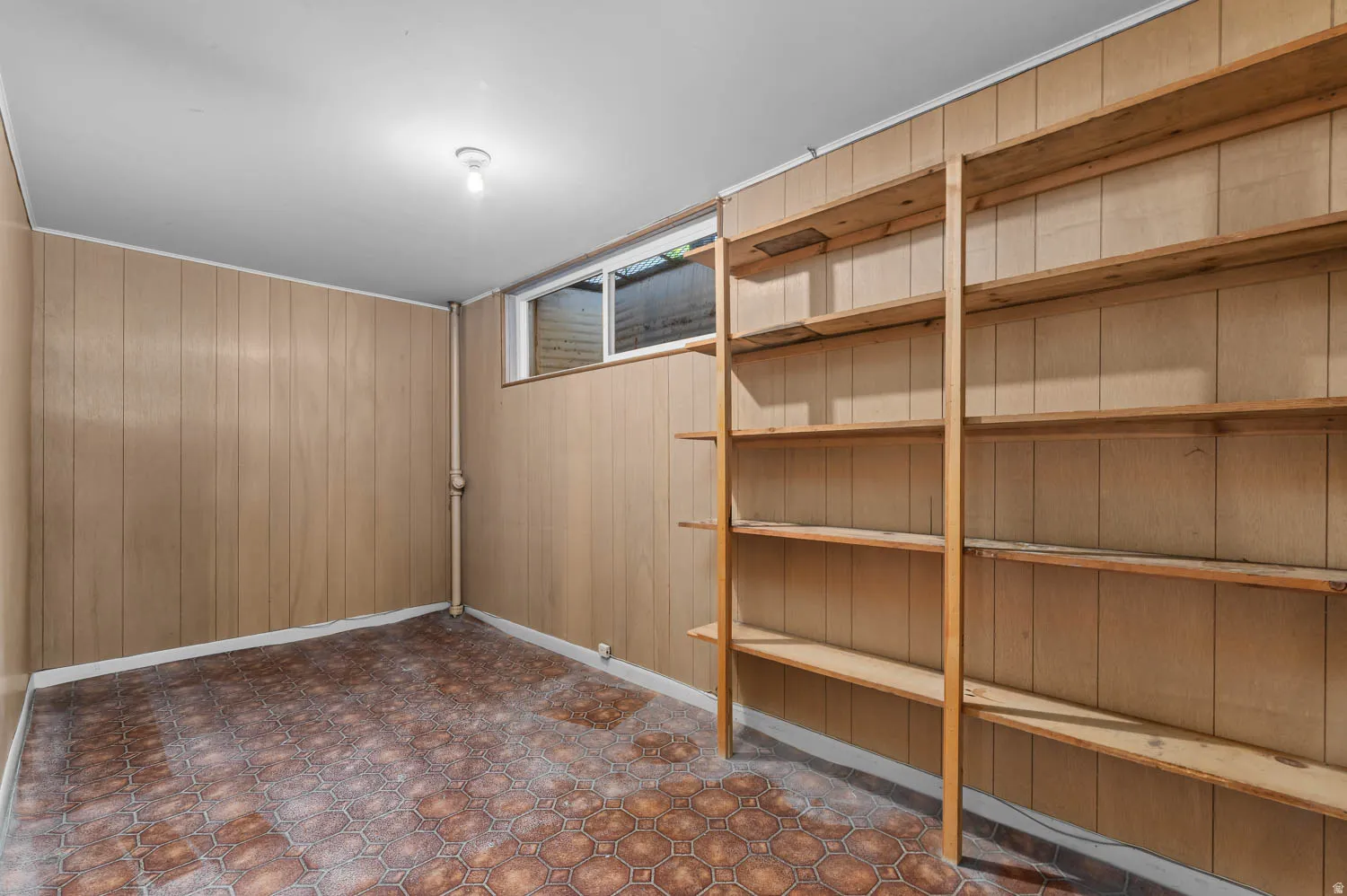 Room featuring wood paneling, a patterned floor, and an exposed window